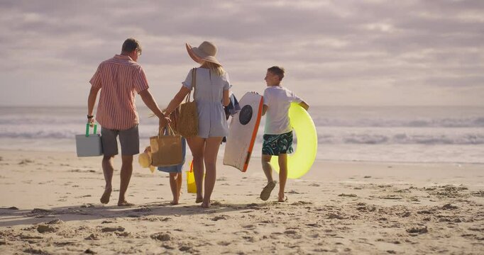 Beach, holding hands and walking with family on sand together for picnic in summer holidays. Nature, travel or vacation with mother, father and children by ocean or sea for weekend bonding from back