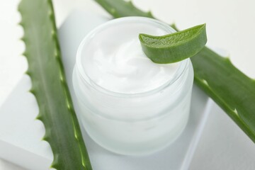 Moisturizing cream with extract of aloe vera and cut leaves on white background, closeup