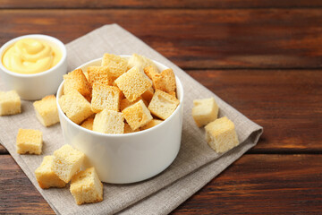 Delicious crispy croutons with sauce on wooden table, closeup. Space for text