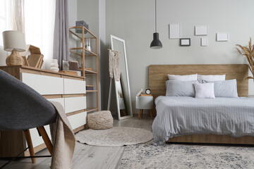 Interior of beautiful bedroom with chest of drawers, shelving unit and mirror