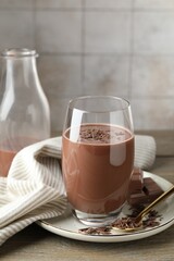 Tasty chocolate milk with shavings and pieces on wooden table
