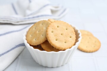 Tasty salty crackers on white tiled table, closeup