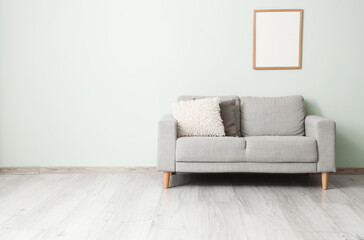 Sofa with pillows and photo frame near grey wall in living room