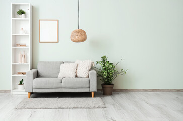 Shelving unit with sofa, houseplant and photo frame near grey wall in living room