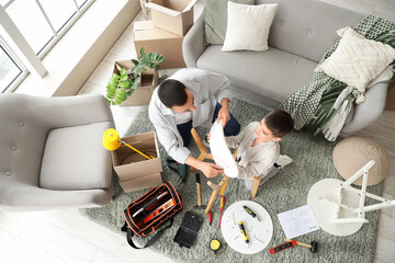 Father with his son assembling chair at home, top view