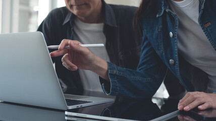 Coworking team brainstorming in modern office. Asian business project team working together at meeting room, having a discussion and analyzing sales data on laptop computer