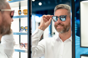 Man in sunglasses indoors portrait. Mature guy choosing eyeglasses. Man in trendy eyewear. 40s man...