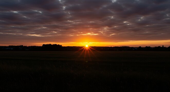 Naturally occurring celestial event end beginning day over open area cultivated field bright visually striking sky dark ground rural landscape under visually appealing multi colored sky end