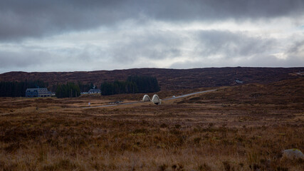 A breathtaking panoramic view of the Scottish Highlands, featuring snow-capped mountains rising above vast open moorland and rugged terrain.