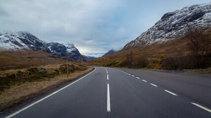 Naklejka premium A breathtaking panoramic view of the Scottish Highlands, featuring snow-capped mountains rising above vast open moorland and rugged terrain.