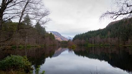A breathtaking panoramic view of the Scottish Highlands, featuring snow-capped mountains rising above vast open moorland and rugged terrain.