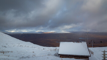  Glencoe Mountain Resort in the Scottish Highlands, featuring snow-covered peaks beneath a heavy,...