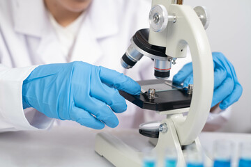 A scientist in blue gloves examines a specimen under a microscope, highlighting the importance of...