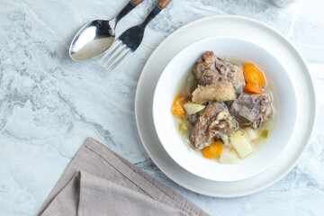 Beef vegetable soup served in a white bowl.