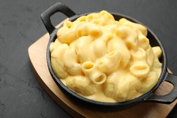 Delicious macaroni and cheese on black table, closeup
