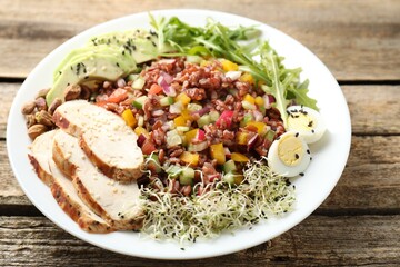 Tasty salad with brown rice on wooden table, closeup
