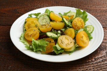 Fresh salad with yellow tomatoes on wooden table, closeup