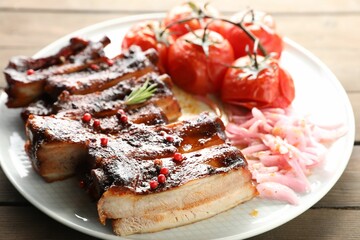 Delicious pork ribs, sun dried tomatoes and onion on wooden table, closeup