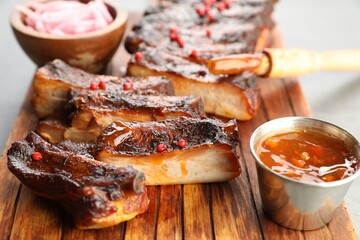 Delicious pork ribs, sauce and brush on grey table, closeup