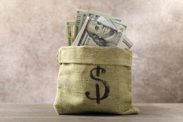 Bag with many dollar banknotes on wooden table