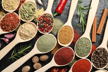 Many different spices in spoons on grey table, flat lay