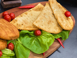 Savory pastry platter garnished with fresh vegetables and chili peppers on a rustic wooden board