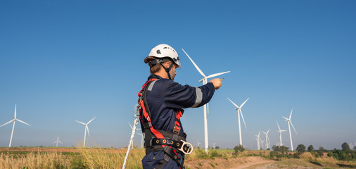 Engineer wearing uniform inspection and survey work in wind turbine farms rotation to generate...