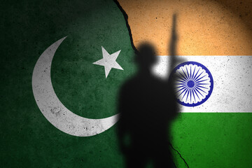 Flags of Pakistan and India painted on the concrete wall with soldier shadow.