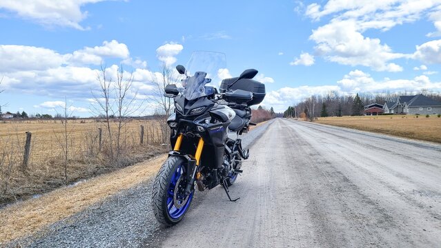 Ottawa, ON Canada - 2024-07-20: Yamaha Tracer 900 GT Motorcycle Parked on Scenic Rural Road Under Blue Sky