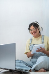Happy student taking notes while attending an online class using laptop and headphones