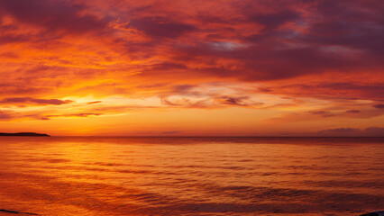 Naklejka premium Fiery Orange and Red Sunset Over Calm Ocean