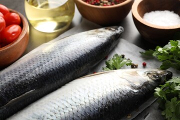 Salted herrings, spices and tomatoes on grey table, closeup
