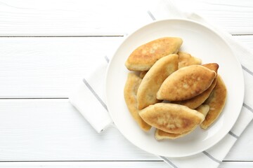 Delicious fried pyrizhky (stuffed pies) on white wooden table, top view. Space for text