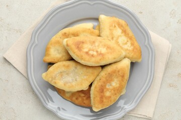 Delicious fried pyrizhky (stuffed pies) on light grey table, top view
