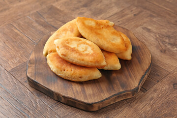 Delicious fried pyrizhky (stuffed pies) on wooden table, closeup
