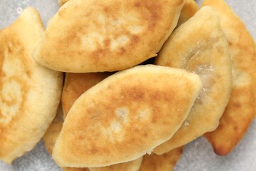 Delicious fried pyrizhky (stuffed pies) on light grey table, top view