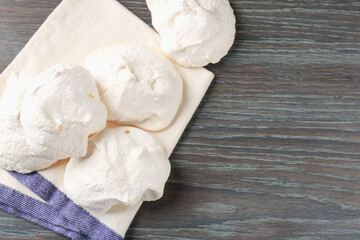 Delicious homemade meringue cookies on wooden table, top view. Space for text