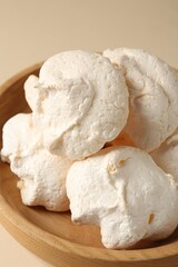 Delicious homemade meringue cookies in bowl on beige background, closeup