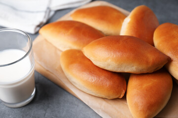 Tasty baked patties and milk on light grey table, closeup