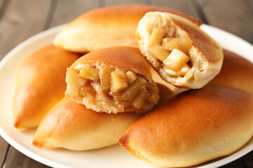 Tasty baked patties with apples on wooden table, closeup
