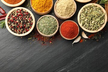 Different aromatic spices on black table, flat lay. Space for text