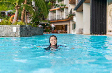 summer by Asian child happy smile in swimming pool or young kid girl fun playing water in waterpark or children people learning swim sports exercise at school or holiday vacation travel at hotel