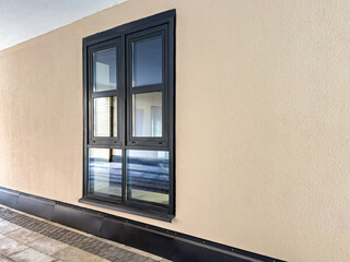 contemporary brown plastic window on beige stucco wall of an old renovated house.