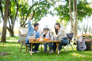 Happy parents and daughter Bakery and Bread Fruit enjoy  in a sunny garden. A joyful summer picnic...
