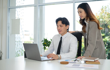 Professional man and woman discussing business data and charts, showcasing corporate analysis and productivity in a contemporary setting.
