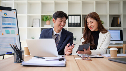 Business partners engaging in productive conversation while reviewing business analytics together in a bright office setting.