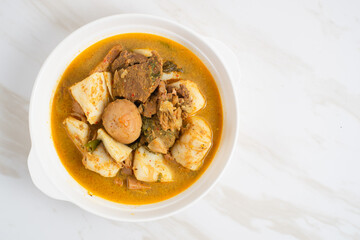 Ketupat Sayur Padang is one of the mainstay dishes from Minang, West Sumatra, Indonesia, served on a white plate with additional coconut curry sauce and jackfruit vegetables, boiled eggs, and rendang.