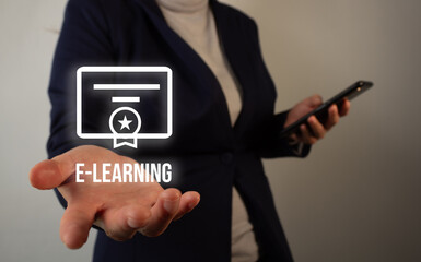 Woman's hand holding an icon of a diploma and the word e-learning while holding a cell phone with...