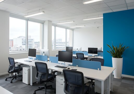 Bright open office space with desks computers chairs and a blue accent wall near large windows