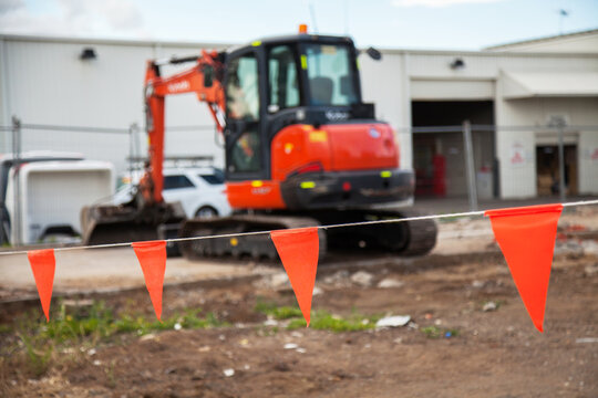 Orange warning fence at worksite with digger